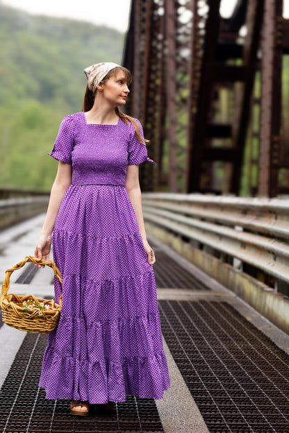 A woman wearing a purple, gingham, five-tiered maxi modest nursing dress