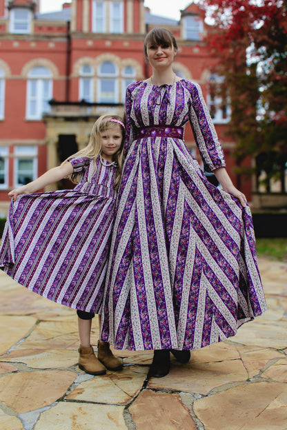 Modest nursing mother and daughter in matching striped dresses outdoors