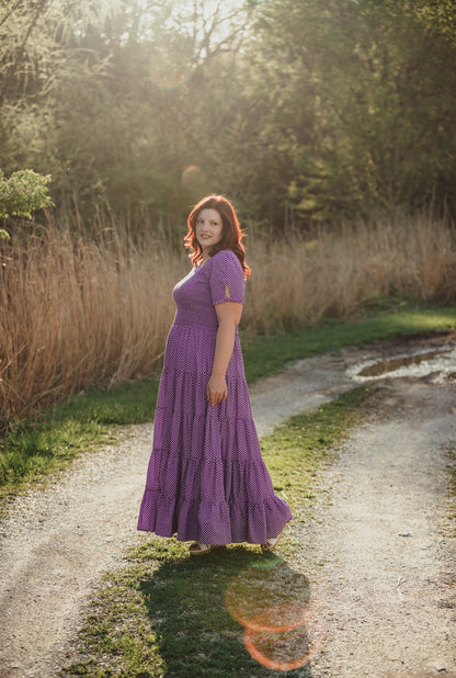 A woman wearing a purple, gingham, five-tiered maxi modest nursing dress