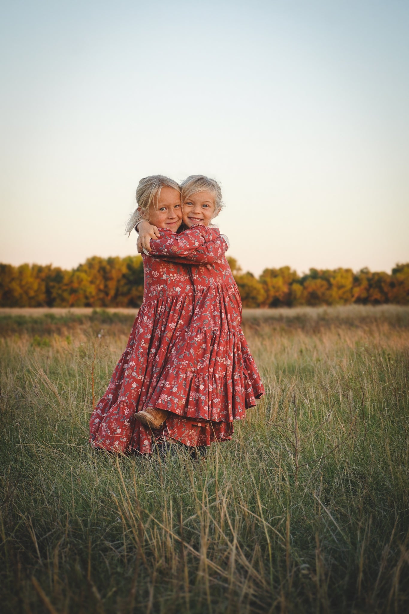 Two children in modest red floral dresses hugging