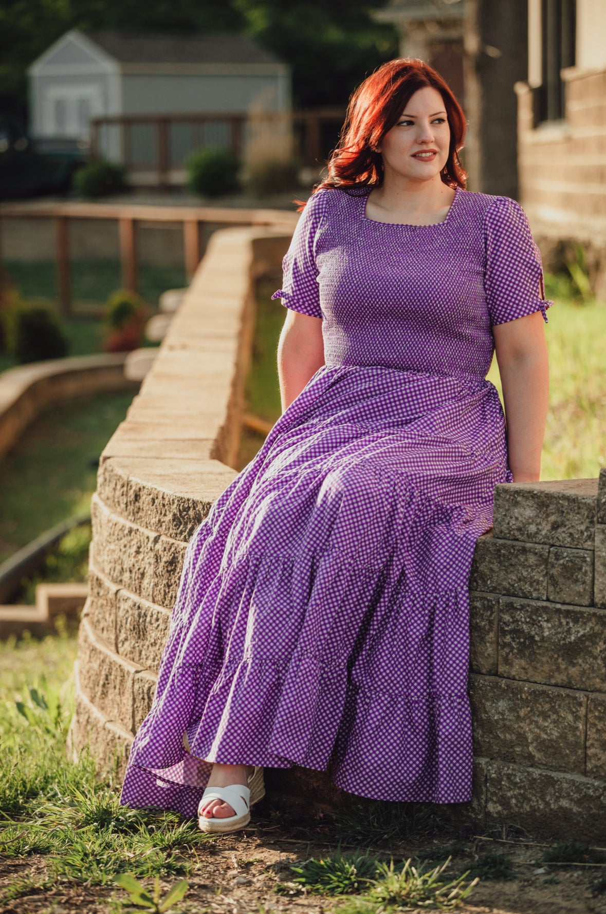 A woman wearing a purple, gingham, five-tiered maxi modest nursing dress
