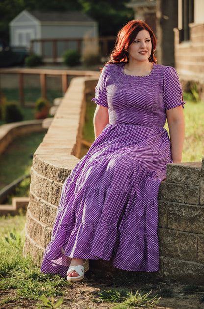 A woman wearing a purple, gingham, five-tiered maxi modest nursing dress