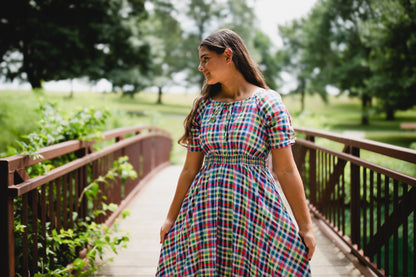 Woman in a colorful modest nursing dress standing on a bridge in a park