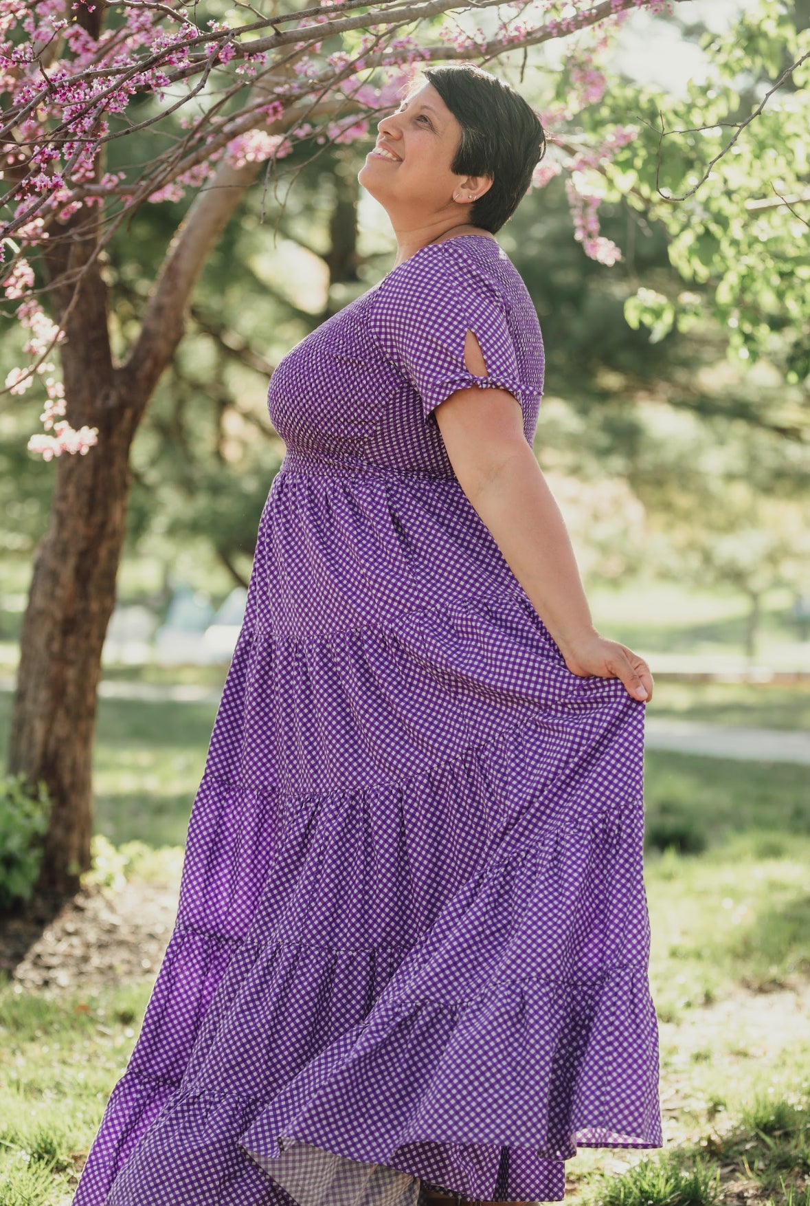 A woman wearing a purple, gingham, five-tiered maxi modest nursing dress