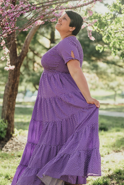A woman wearing a purple, gingham, five-tiered maxi modest nursing dress