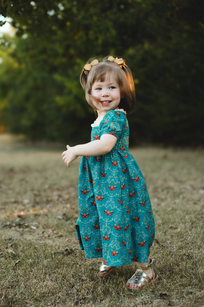 Child wearing modest dress with patterns on grass