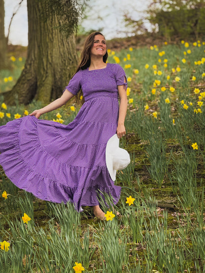 A woman wearing a purple, gingham, five-tiered maxi modest nursing dress