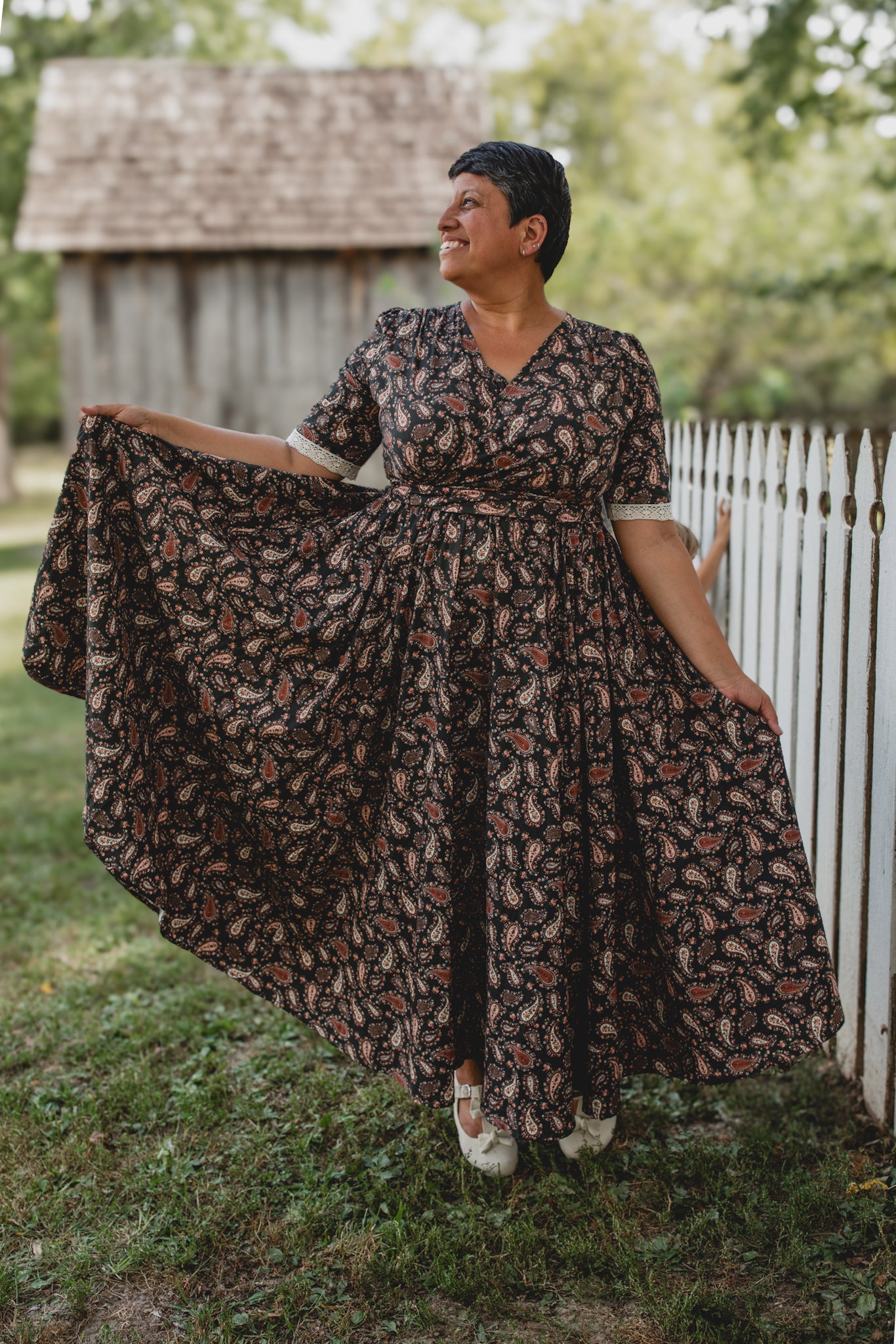 woman in a modest nursing dress near white picket fence