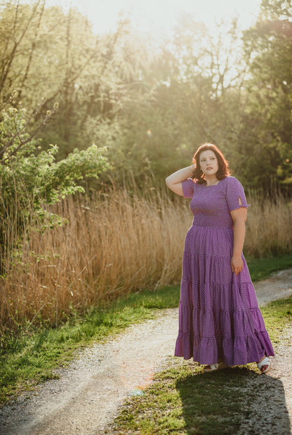 A woman wearing a purple, gingham, five-tiered maxi modest nursing dress