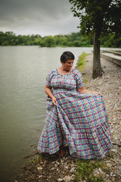 Woman in a plaid modest nursing dress sitting by a lake on a cloudy day