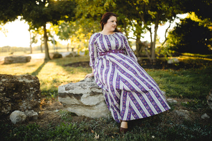 Modest nursing woman in striped dress sitting on rock