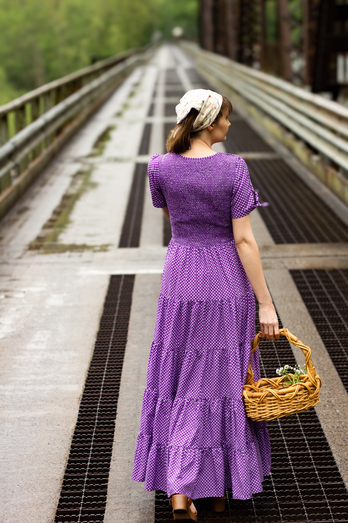 A woman wearing a purple, gingham, five-tiered maxi modest nursing dress