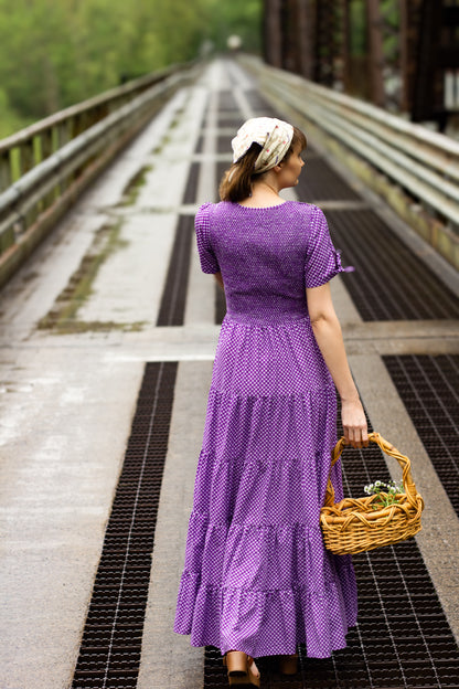 A woman wearing a purple, gingham, five-tiered maxi modest nursing dress