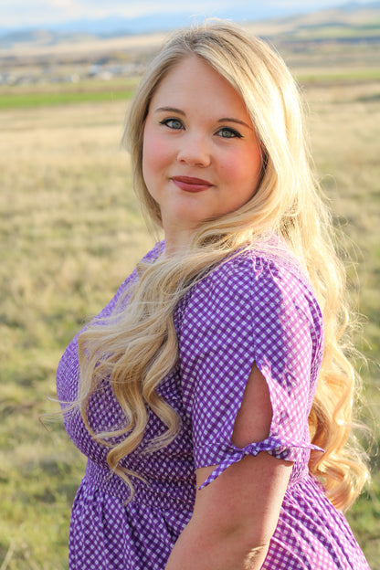 A woman wearing a purple, gingham, five-tiered maxi modest nursing dress