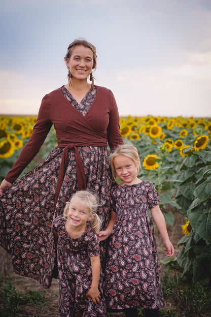 Woman in modest nursing dress with two girls in sunflower field