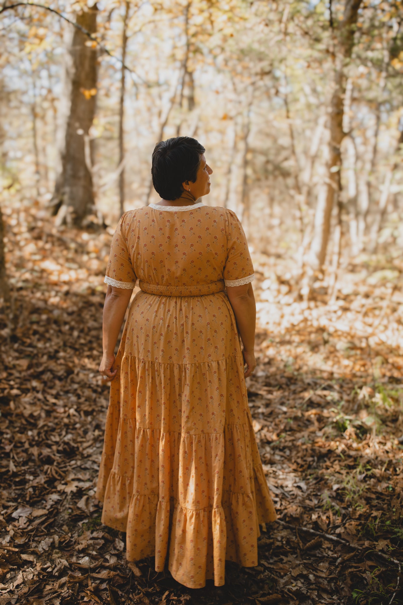 Woman in modest nursing dress forest autumn leaves