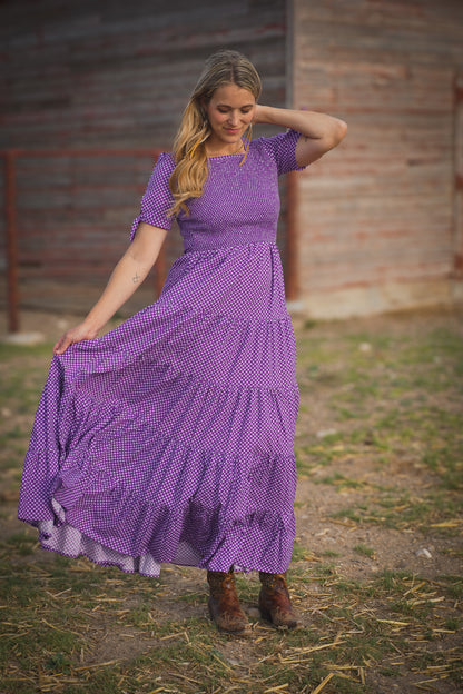A woman wearing a purple, gingham, five-tiered maxi modest nursing dress
