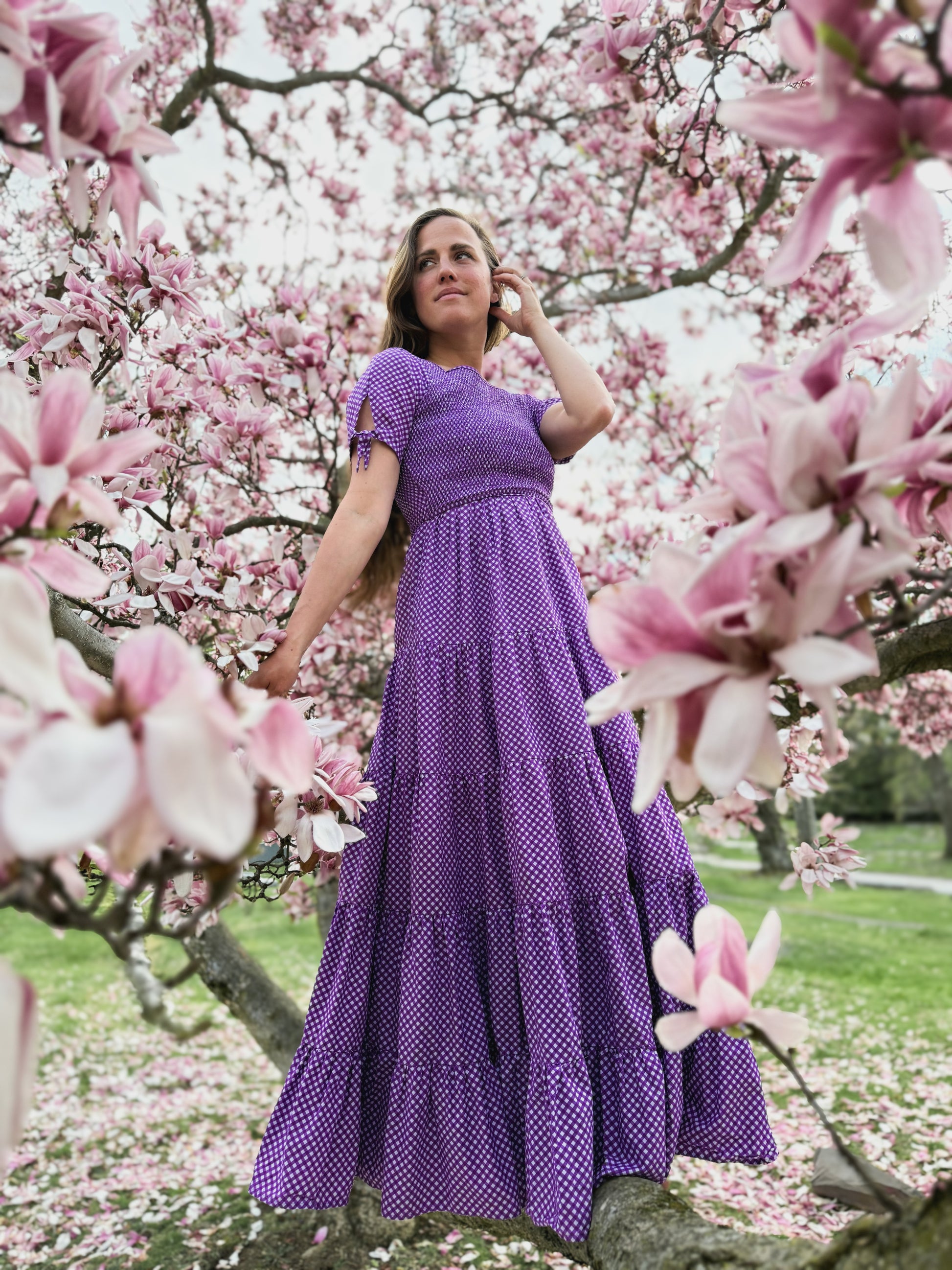 A woman wearing a purple, gingham, five-tiered maxi modest nursing dress