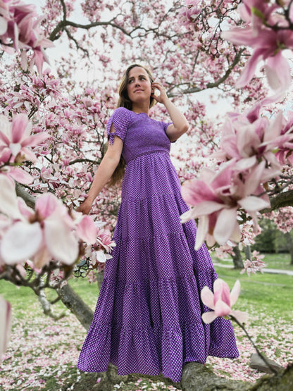 A woman wearing a purple, gingham, five-tiered maxi modest nursing dress