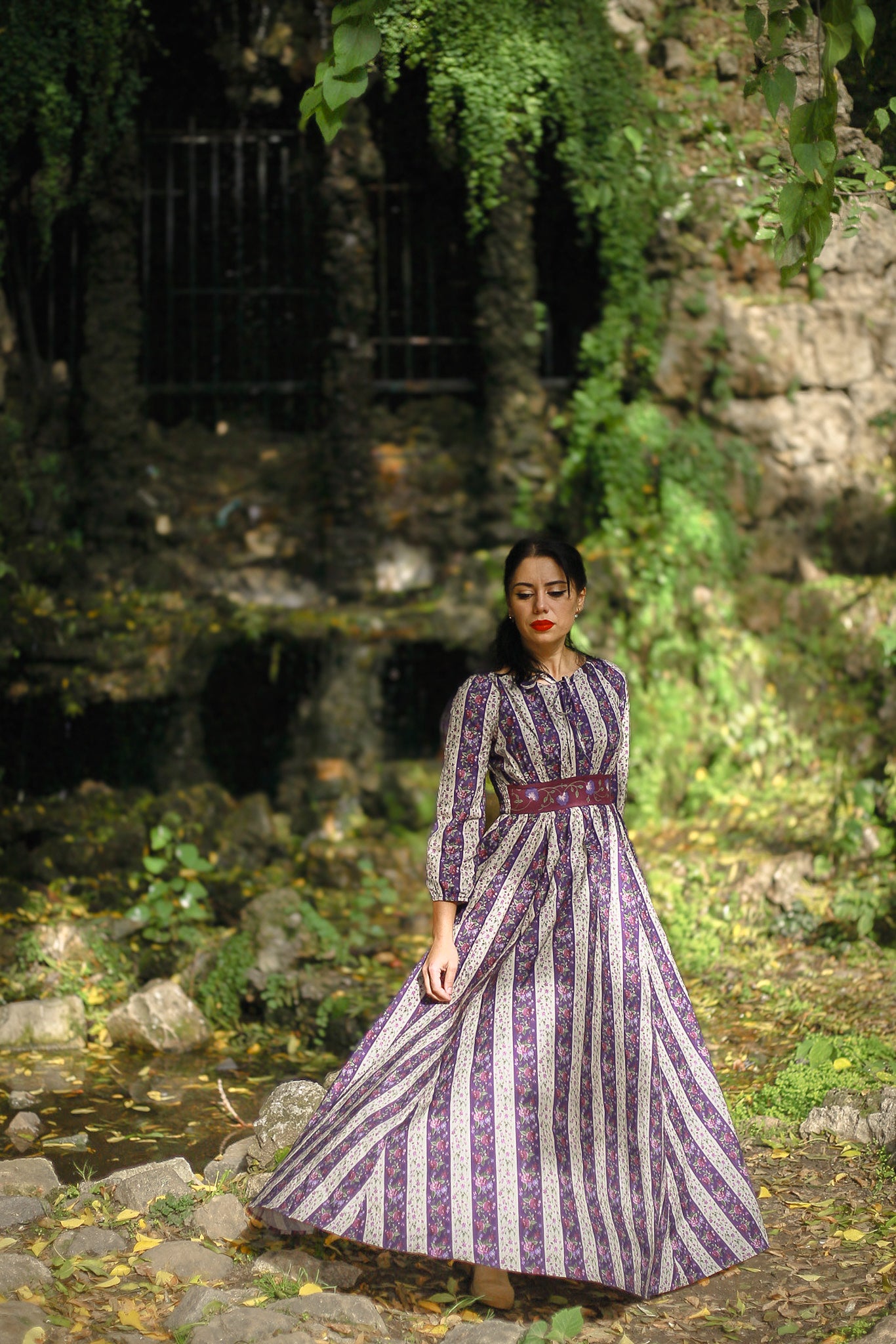 Modest nursing woman in purple striped dress outdoors with rocks