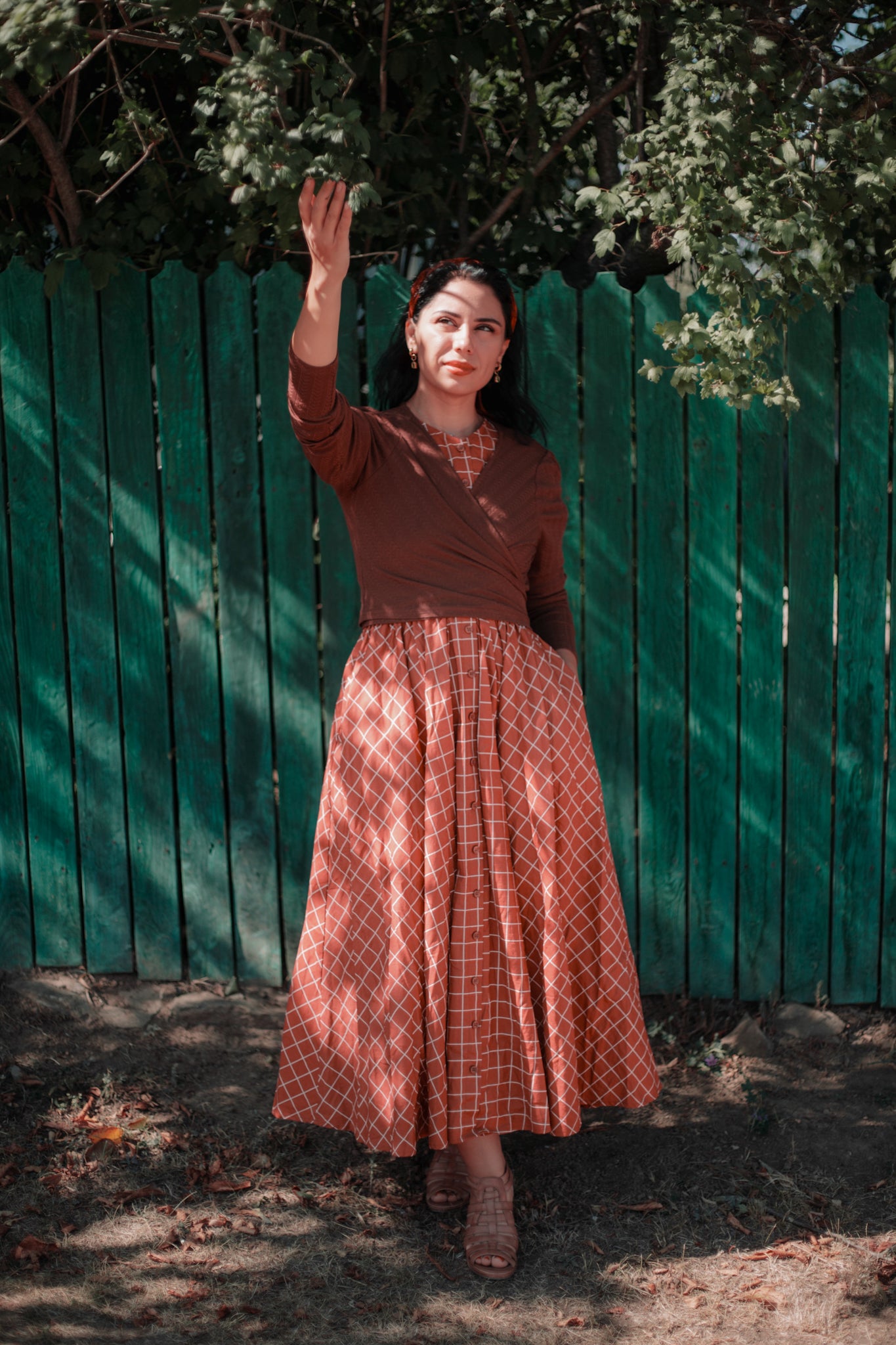 Woman in modest nursing plaid dress near fence