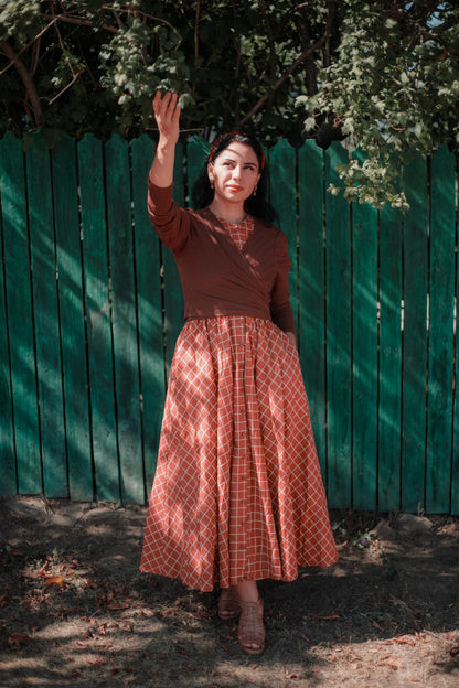 Woman in modest nursing plaid dress near fence