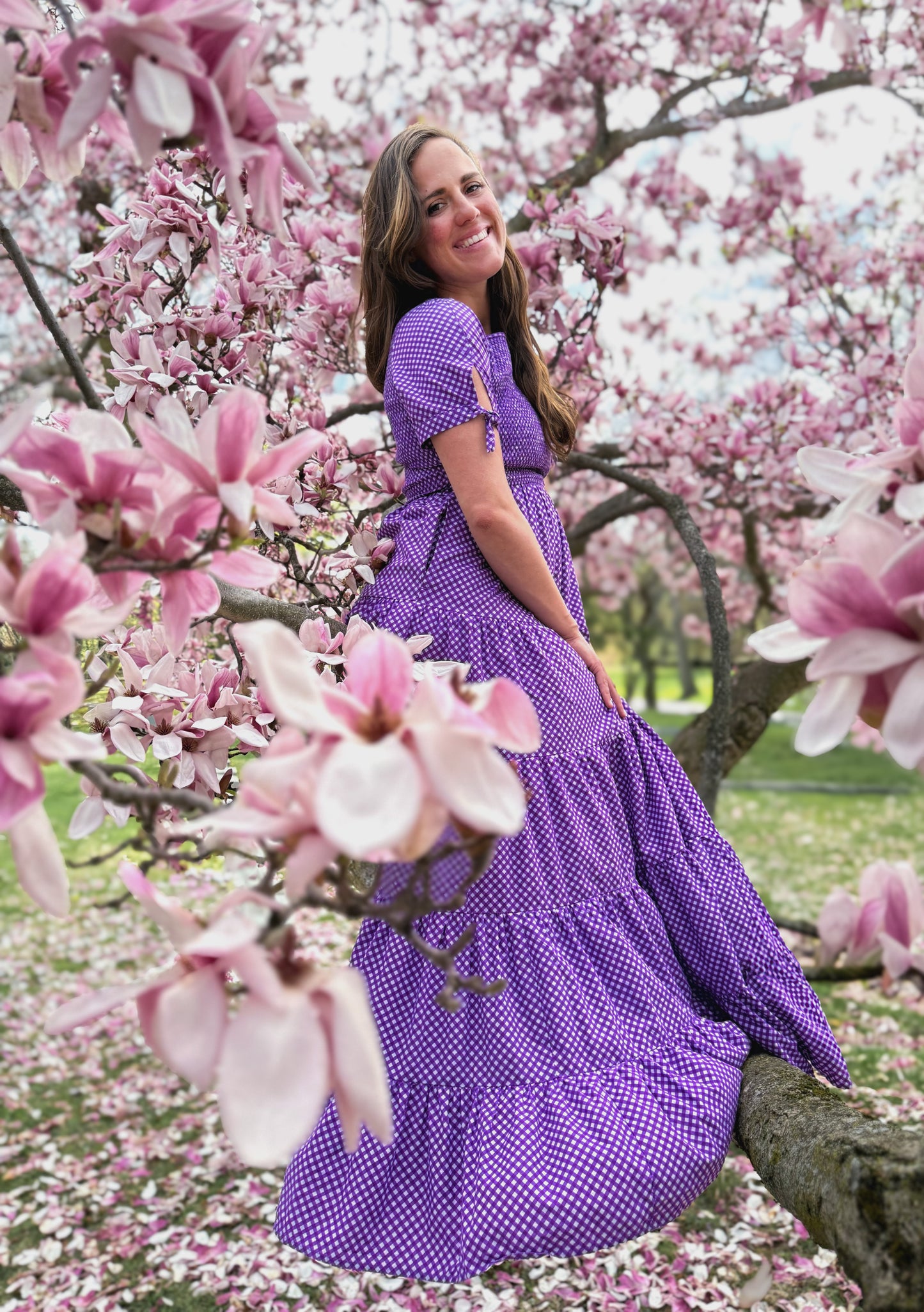 A woman wearing a purple, gingham, five-tiered maxi modest nursing dress