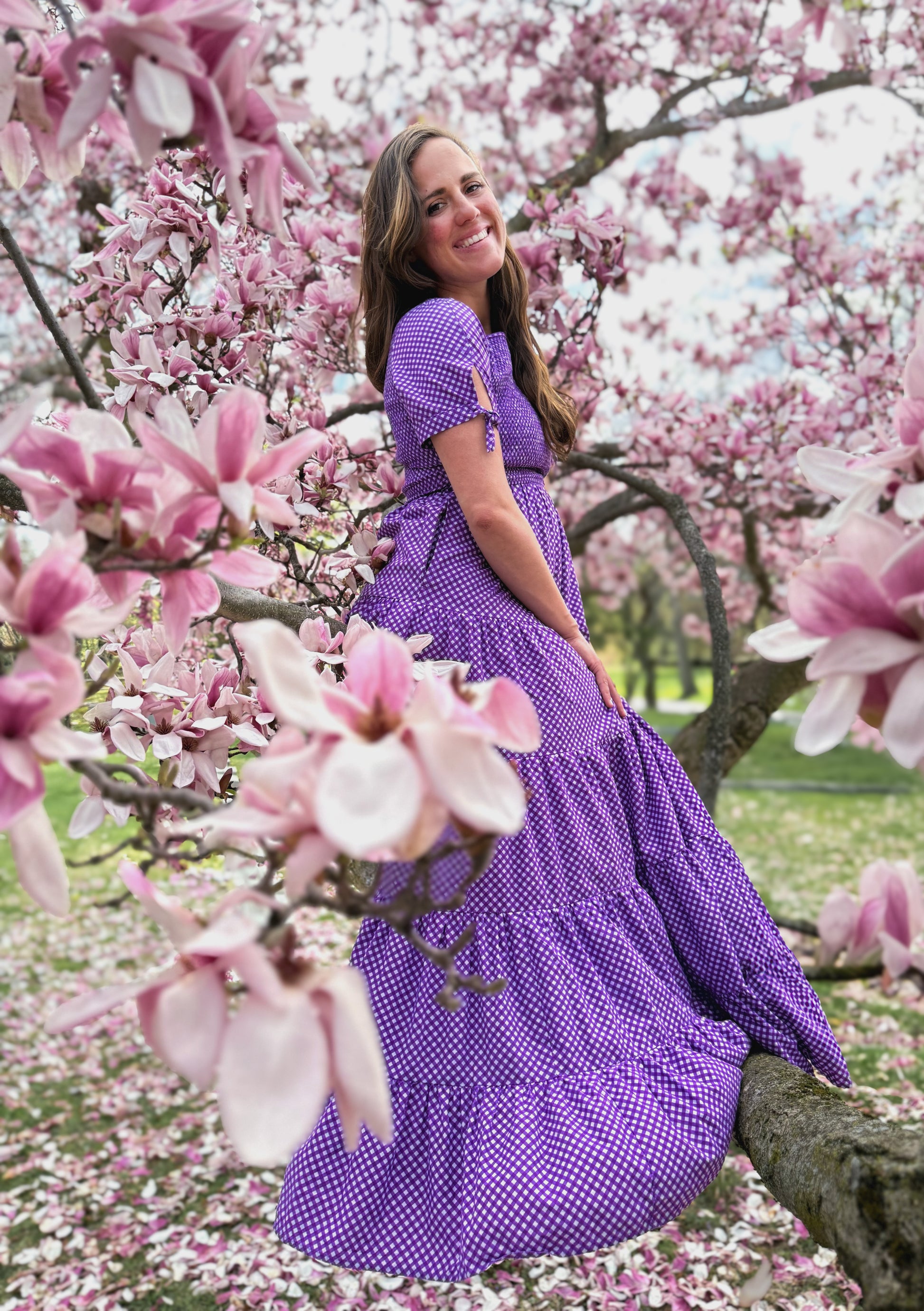 A woman wearing a purple, gingham, five-tiered maxi modest nursing dress