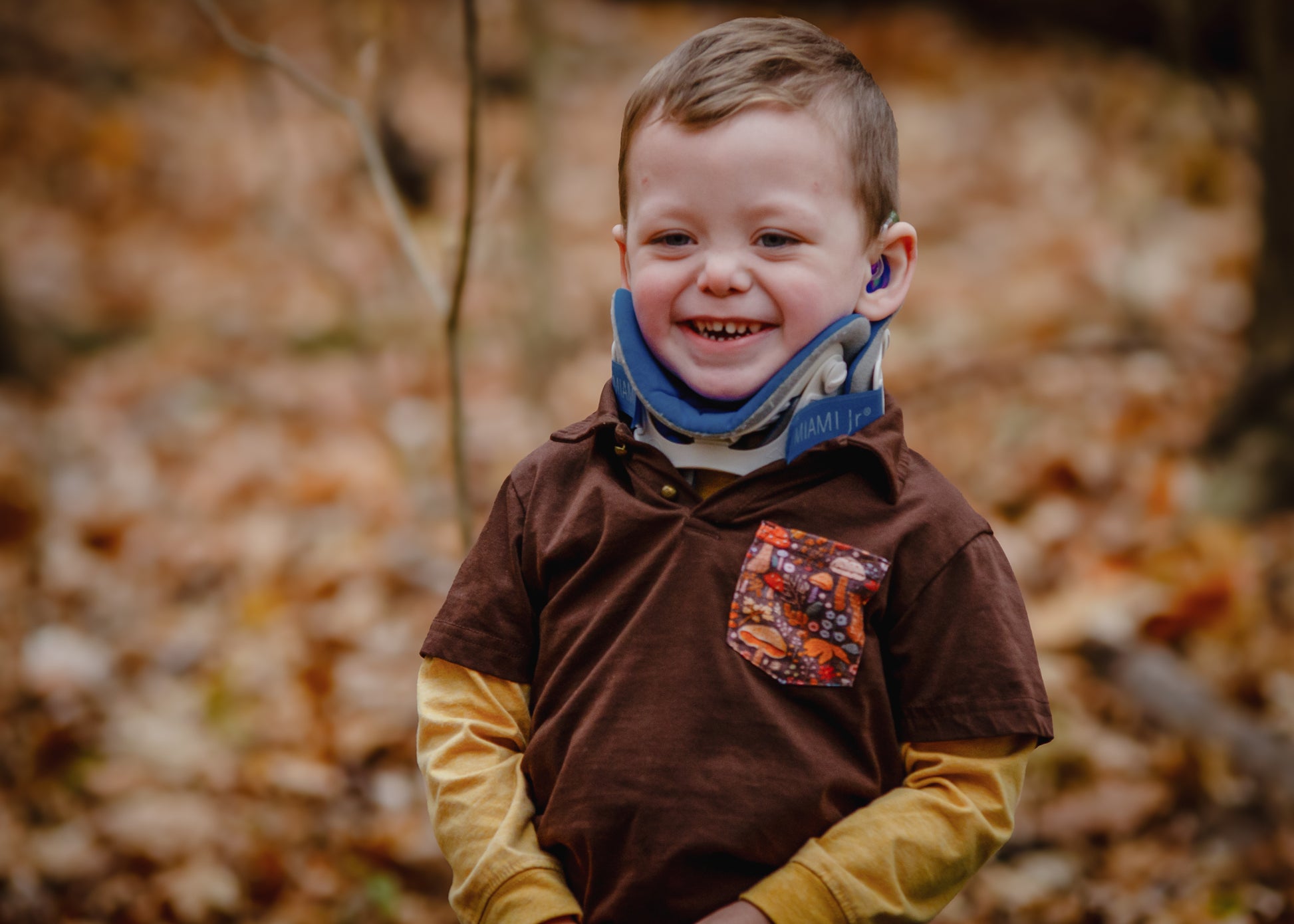 Child smiling in brown shirt with pocket