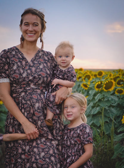 woman wearing a modest nursing black patterned dress with her children