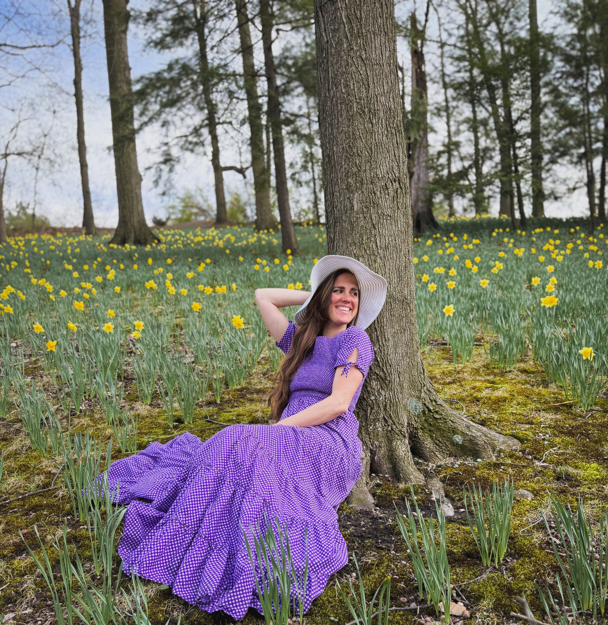 A woman wearing a purple, gingham, five-tiered maxi modest nursing dress