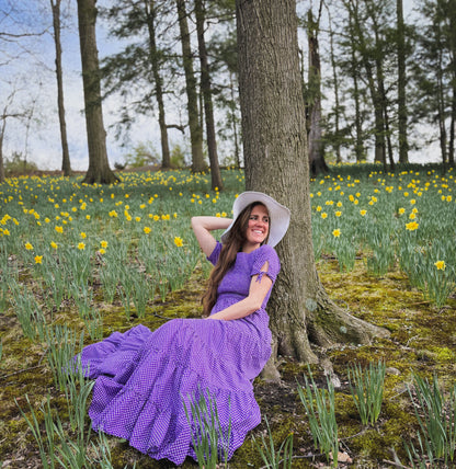 A woman wearing a purple, gingham, five-tiered maxi modest nursing dress