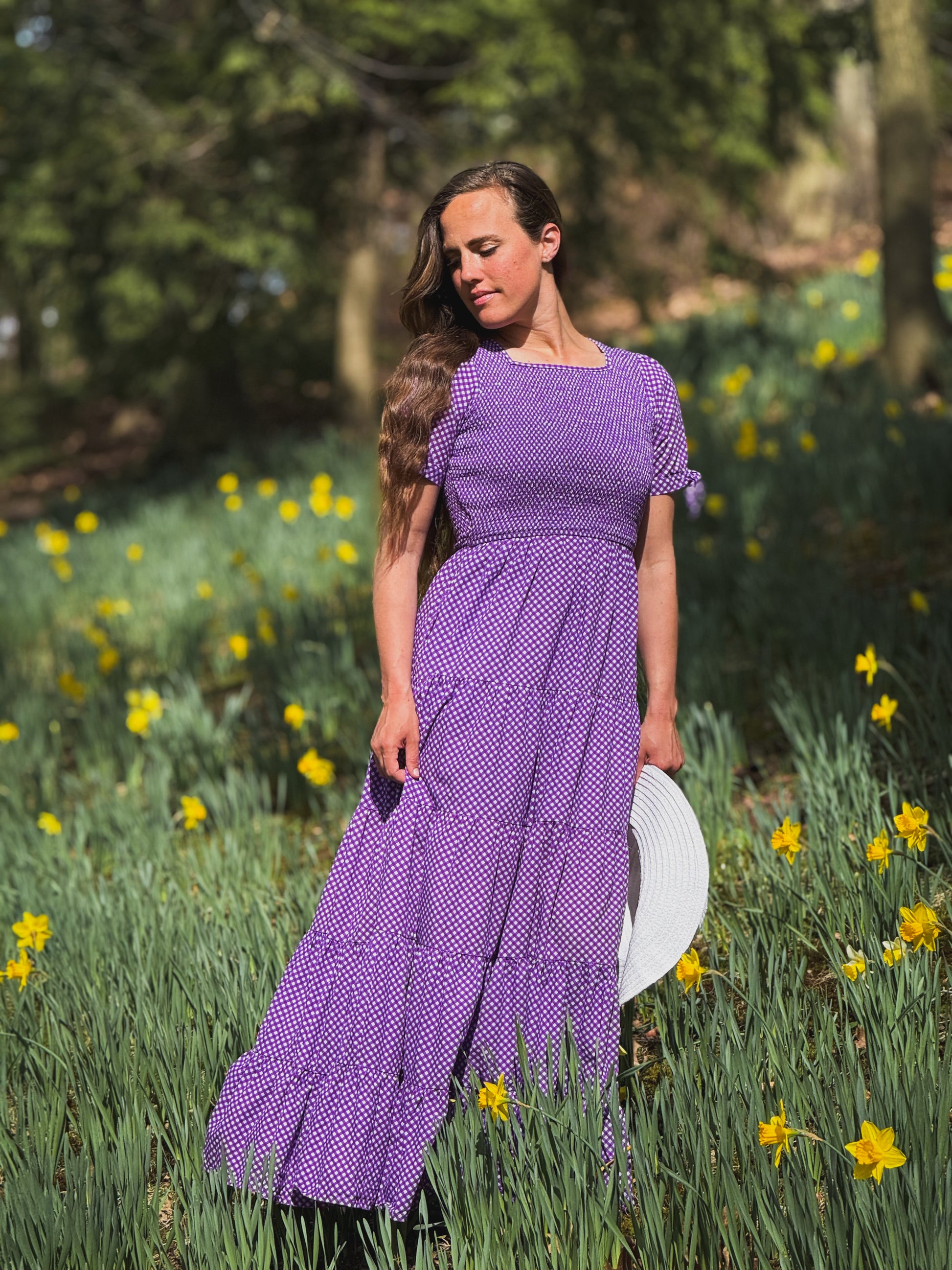 A woman wearing a purple, gingham, five-tiered maxi modest nursing dress