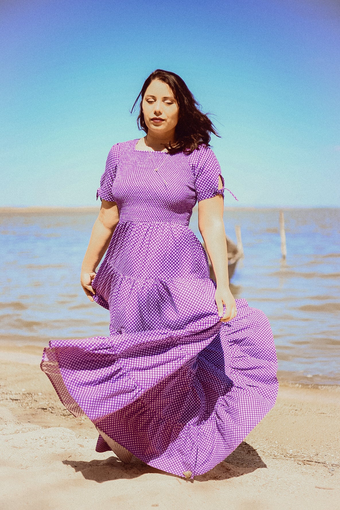 A woman wearing a purple, gingham, five-tiered maxi modest nursing dress