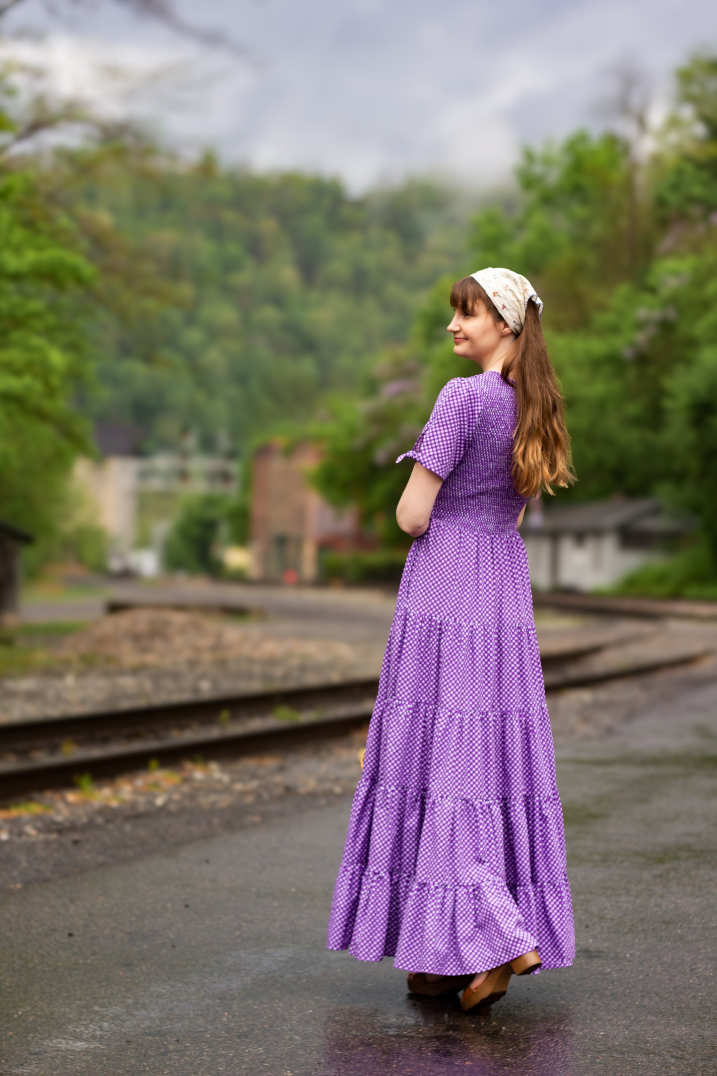 A woman wearing a purple, gingham, five-tiered maxi modest nursing dress