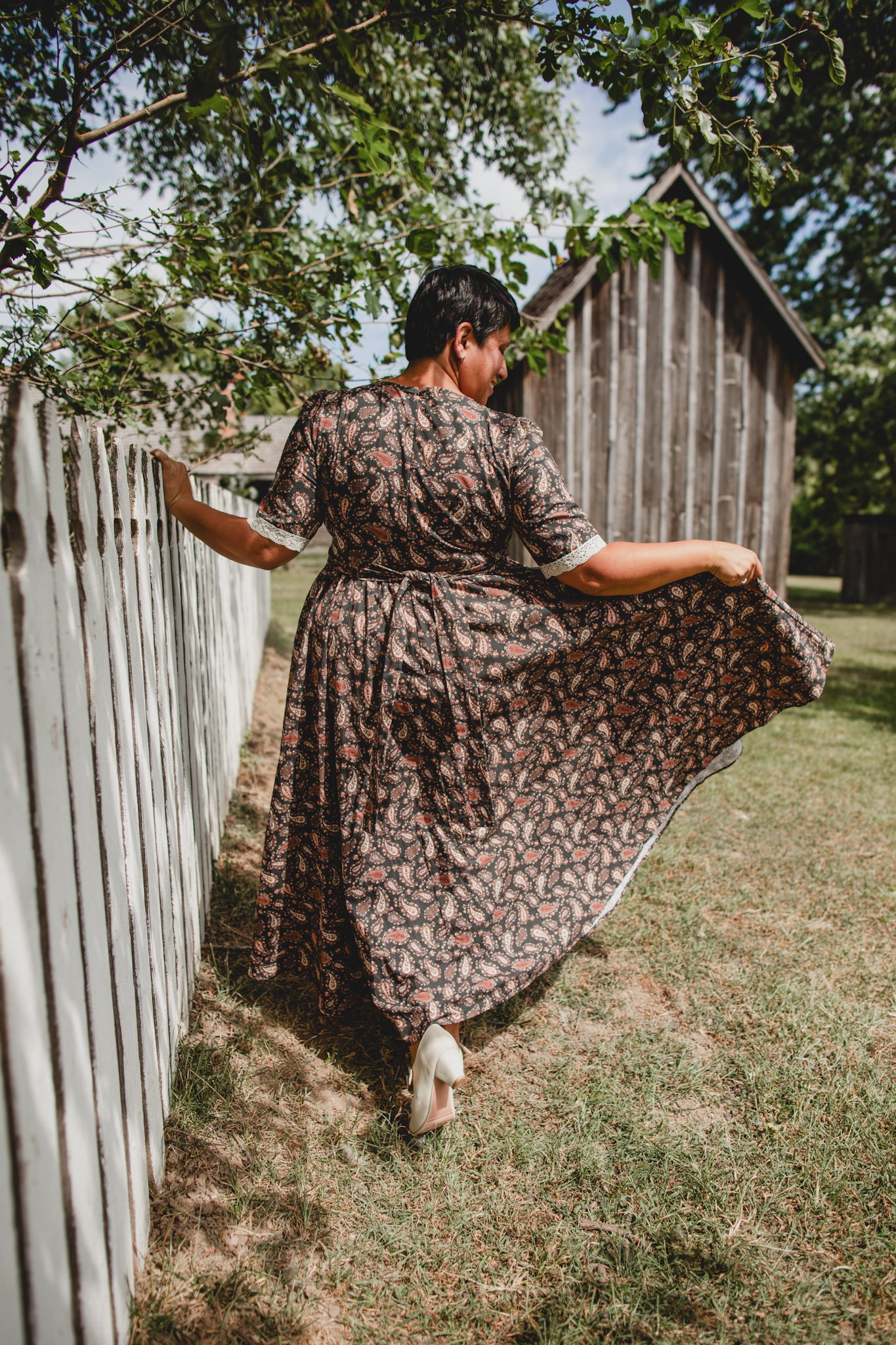 Woman in modest nursing dress by wooden fence