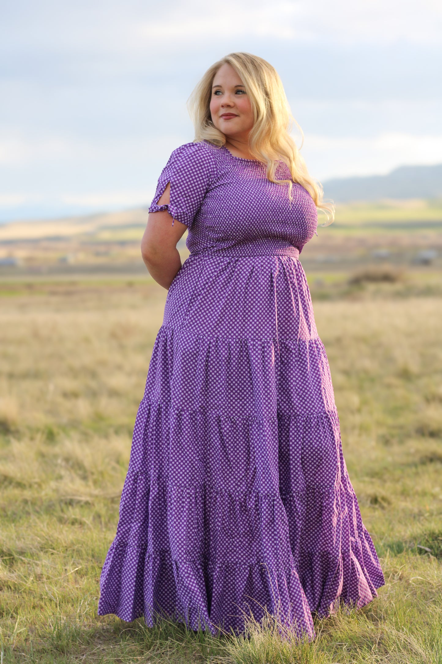 A woman wearing a purple, gingham, five-tiered maxi modest nursing dress