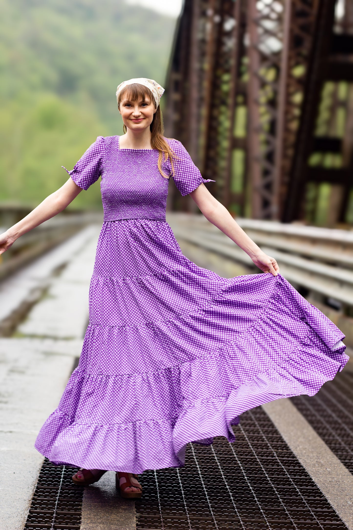 A woman wearing a purple, gingham, five-tiered maxi modest nursing dress
