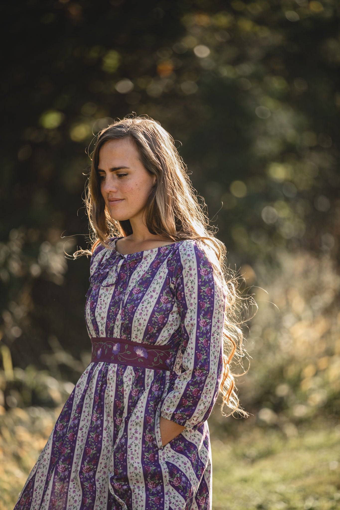 Modest nursing woman in purple patterned dress outdoors