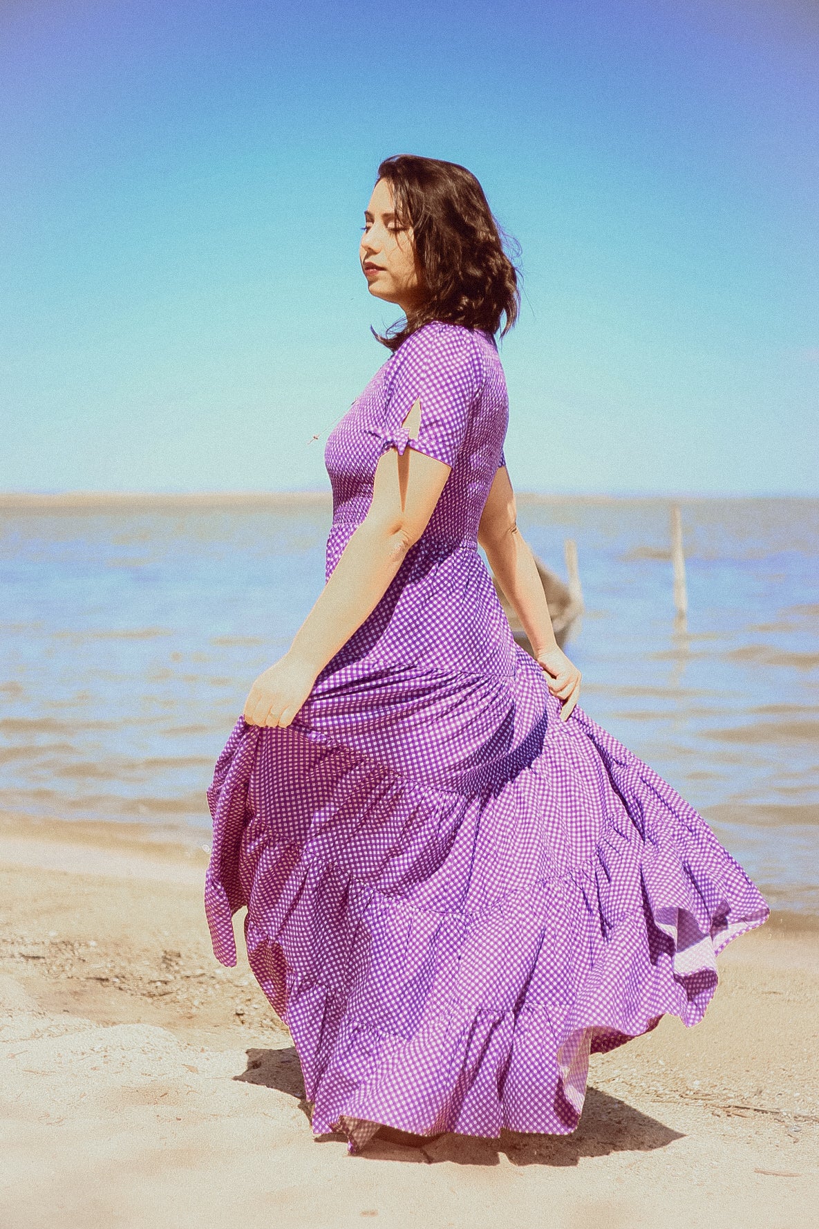 A woman wearing a purple, gingham, five-tiered maxi modest nursing dress