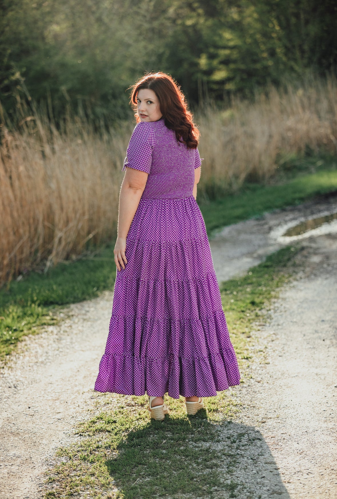 A woman wearing a purple, gingham, five-tiered maxi modest nursing dress