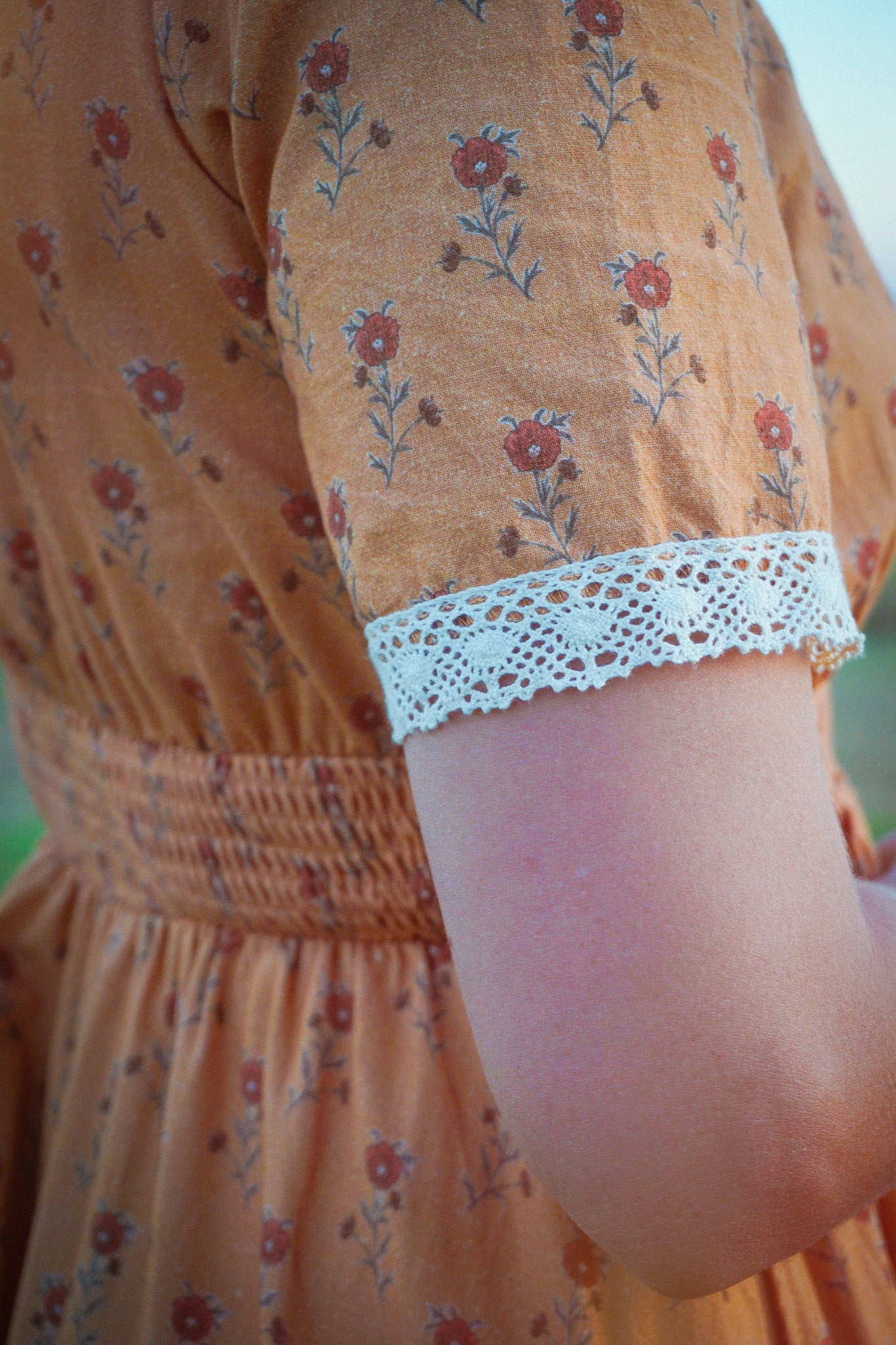 Close-up orange floral dress lace cuffs