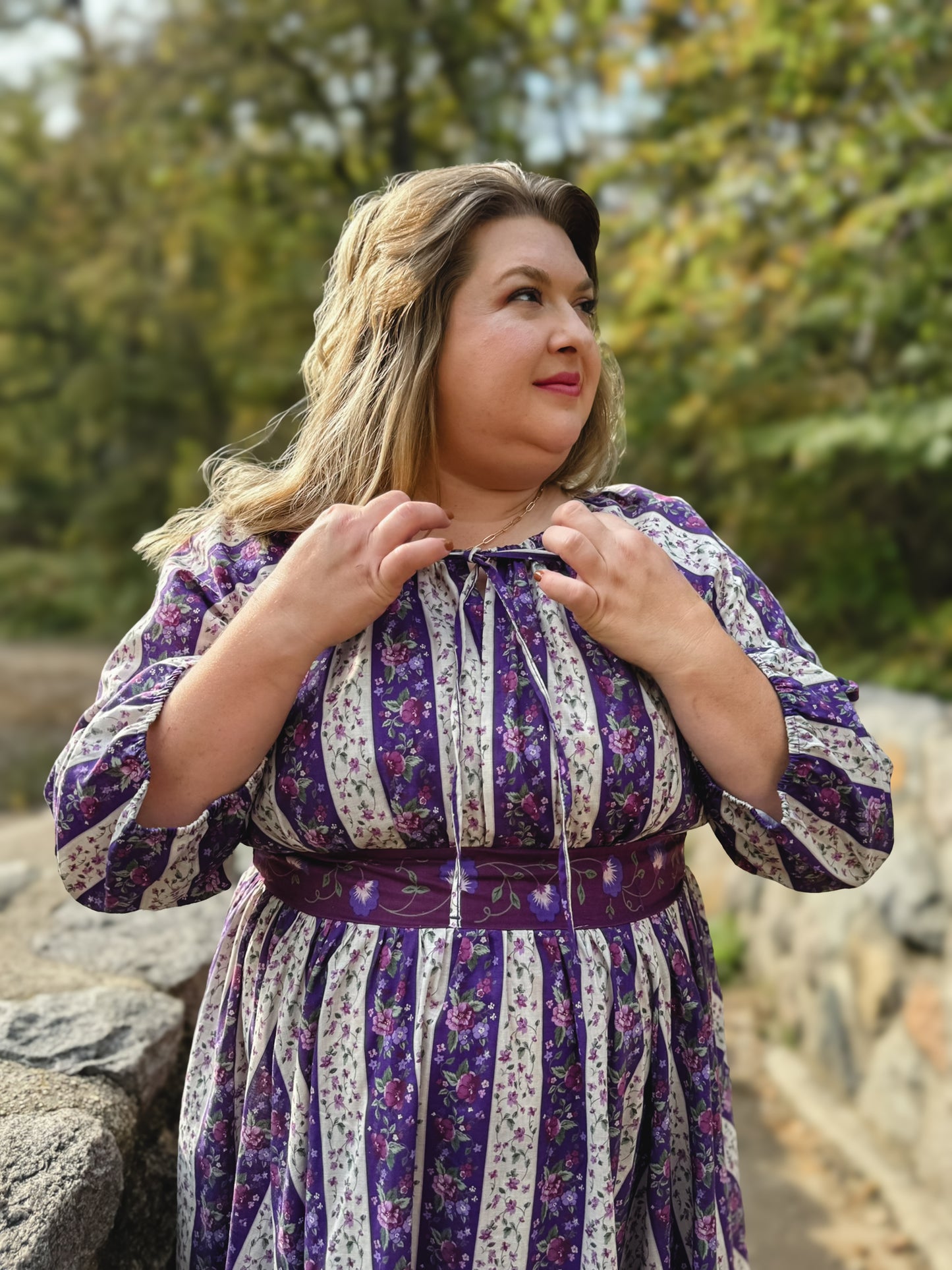 Modest nursing woman in purple patterned dress outdoors