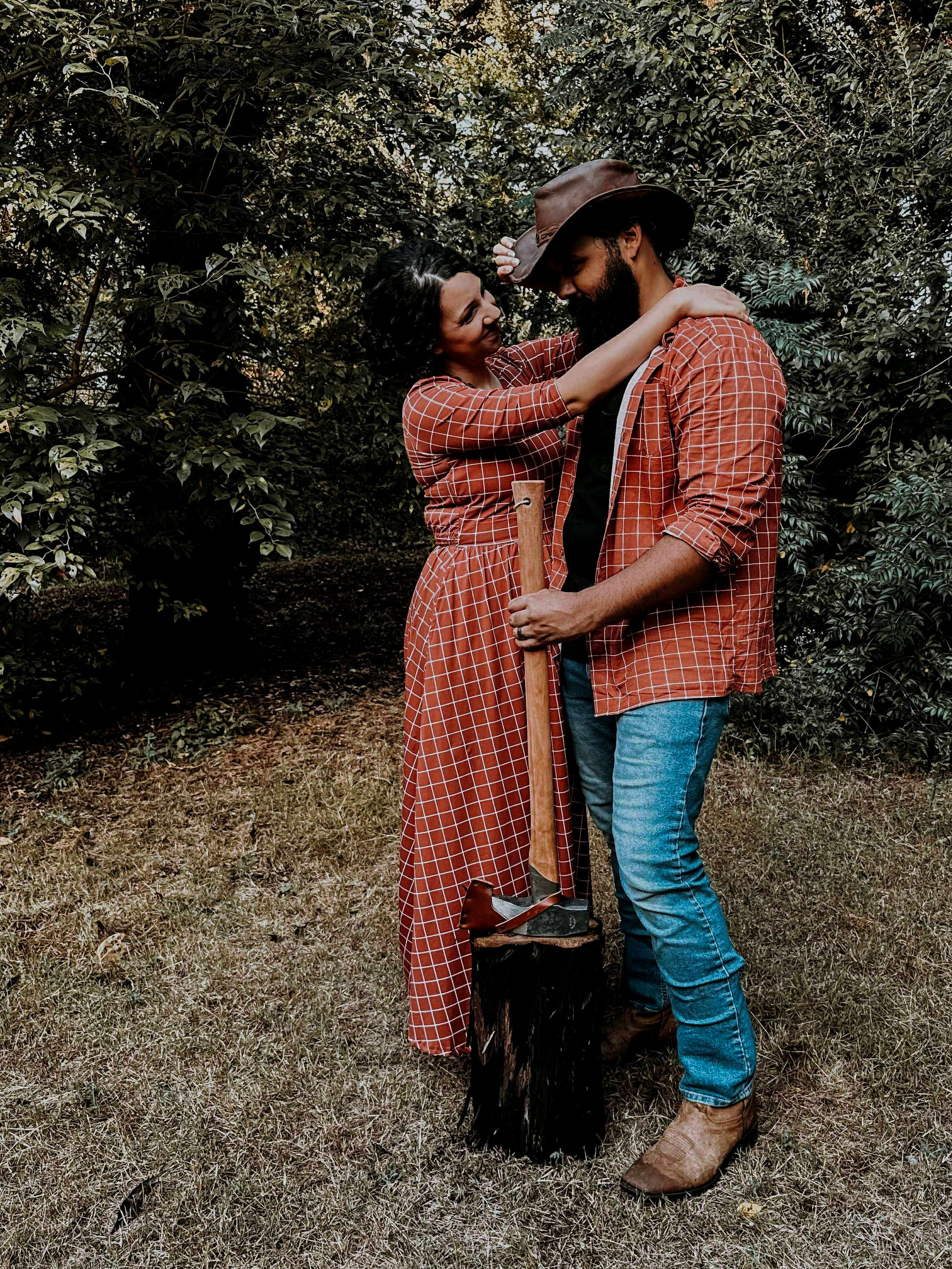 Two people embracing outdoors with a person holding a shovel.
