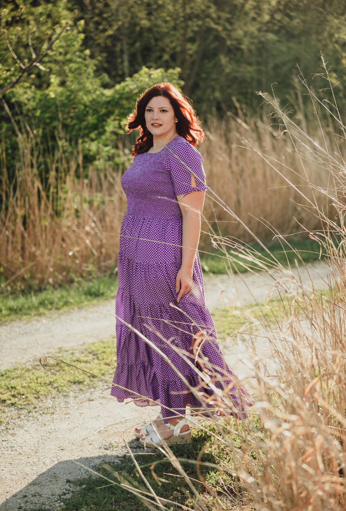 A woman wearing a purple, gingham, five-tiered maxi modest nursing dress