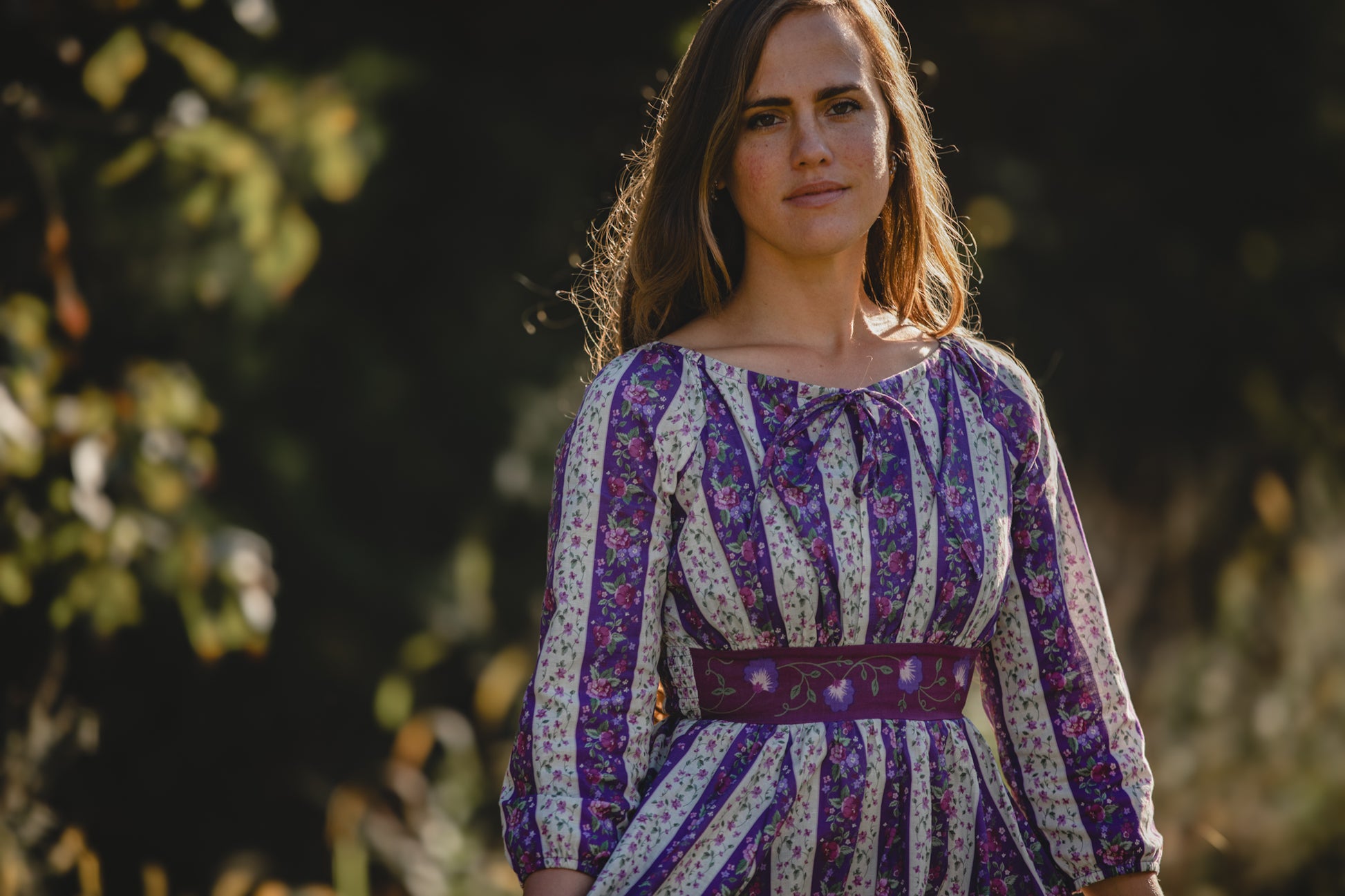 Modest nursing woman in patterned dress with blurred background