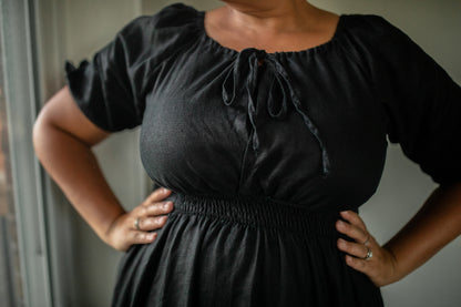 Person wearing a black modest nursing dress with puff sleeves against a neutral background