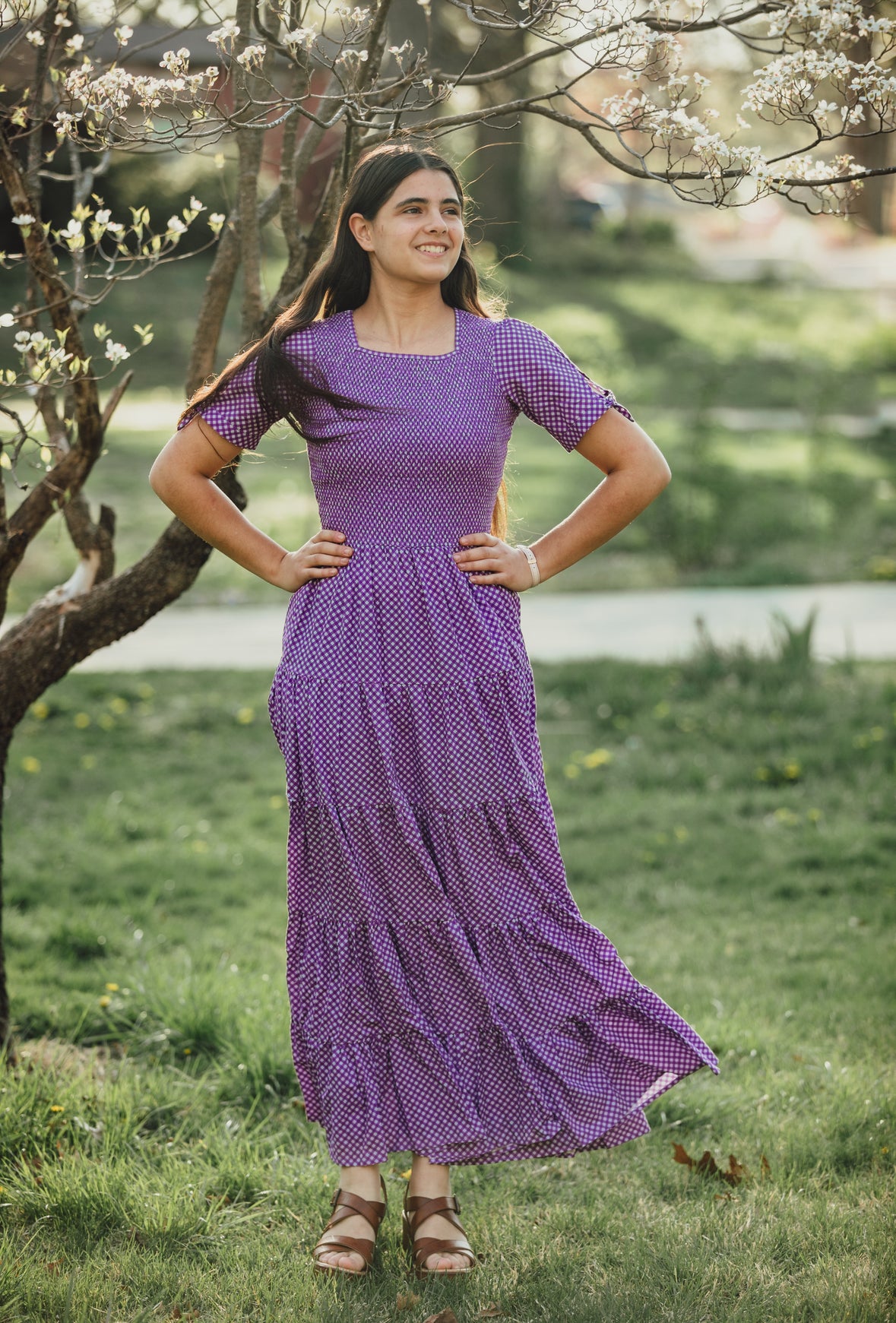 A woman wearing a purple, gingham, five-tiered maxi modest nursing dress