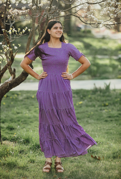 A woman wearing a purple, gingham, five-tiered maxi modest nursing dress