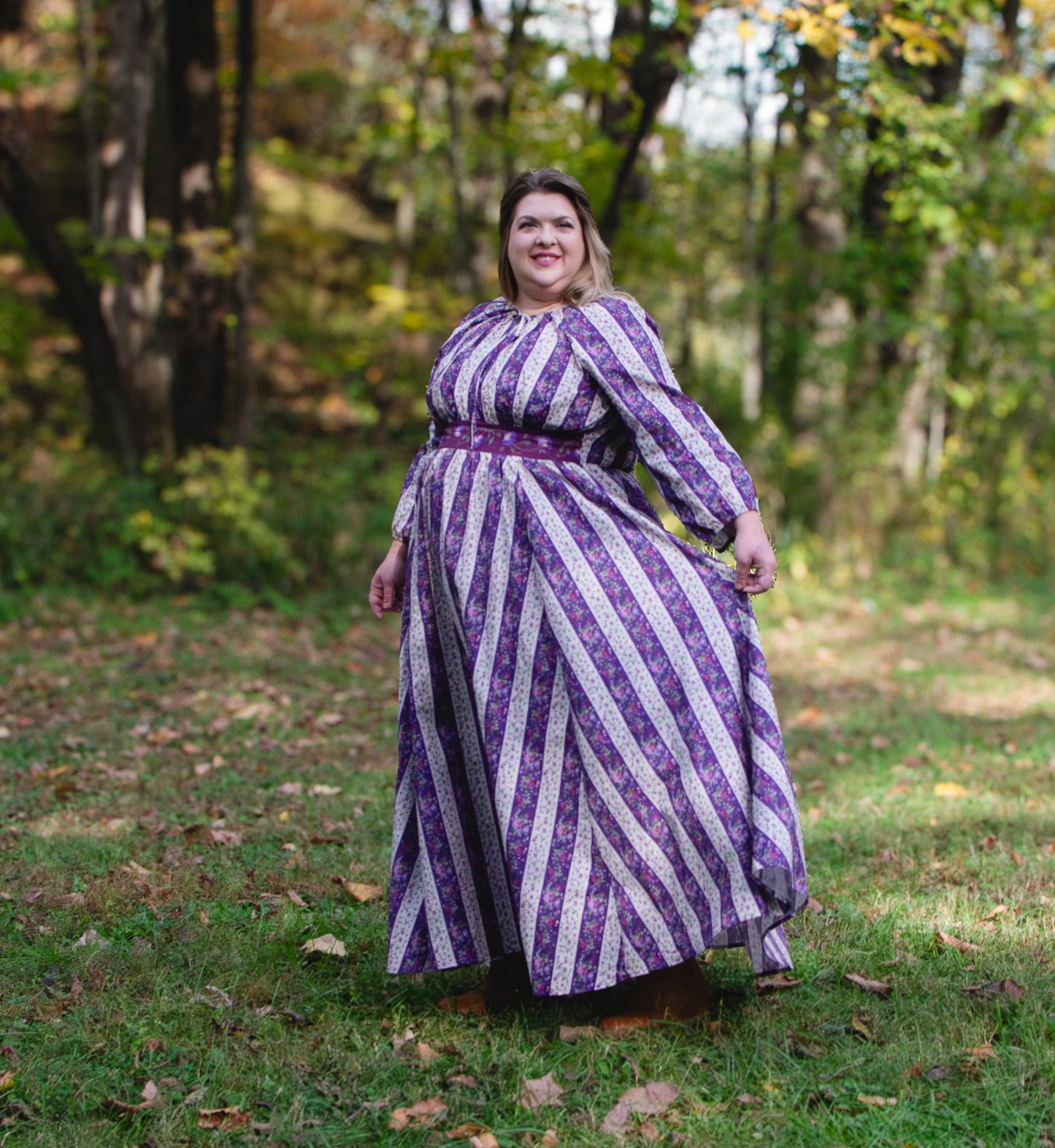 Woman wearing a modest nursing purple and white striped dress standing in a forest.